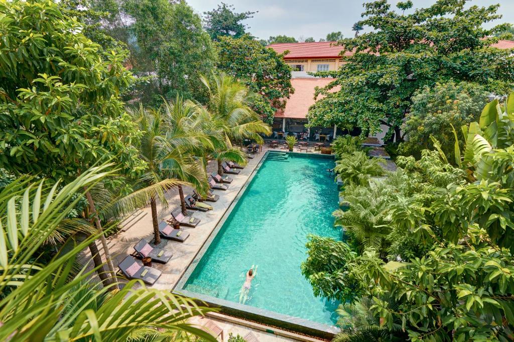 uma vista sobre uma piscina com cadeiras e árvores em Plantation Urban Resort & Spa em Phnom Penh