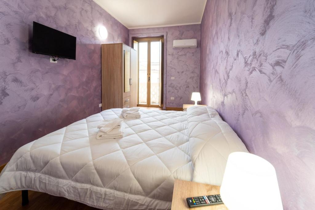 1 dormitorio con cama blanca y paredes moradas en B&B Sasso en Cosenza