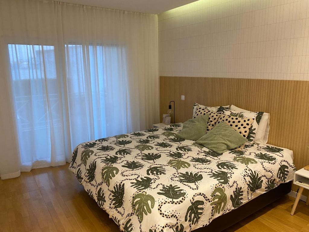 a bedroom with a bed with a green and white comforter at Garden Hill Apartment in Albufeira