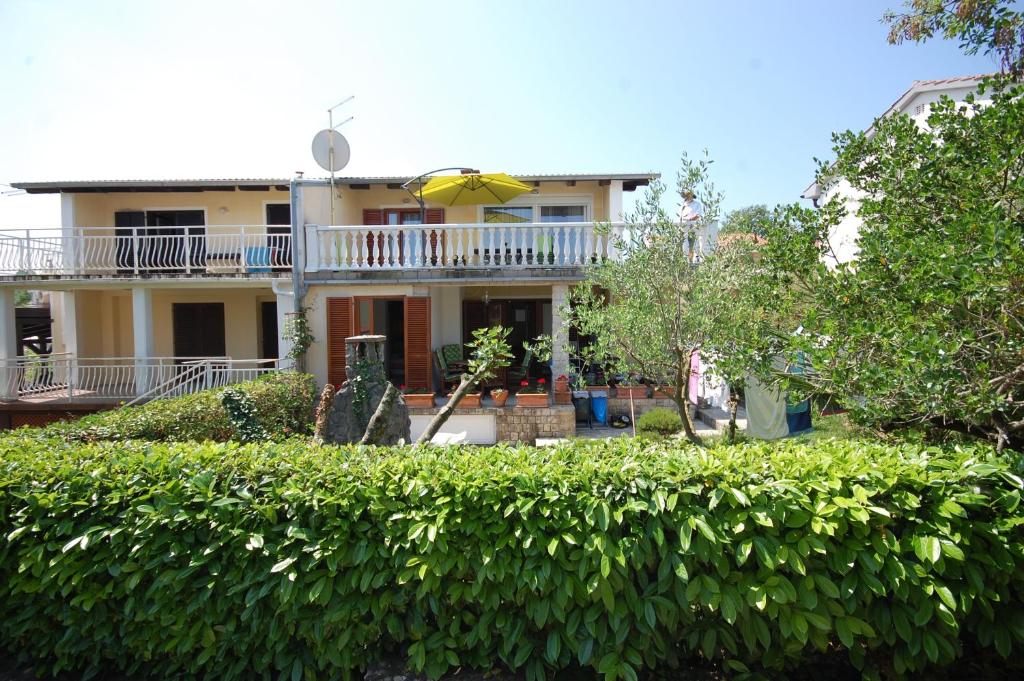 ein Haus mit einem Regenschirm und einer Hecke in der Unterkunft Apartments with parking space Vantacici, Krk - 20507 in Malinska