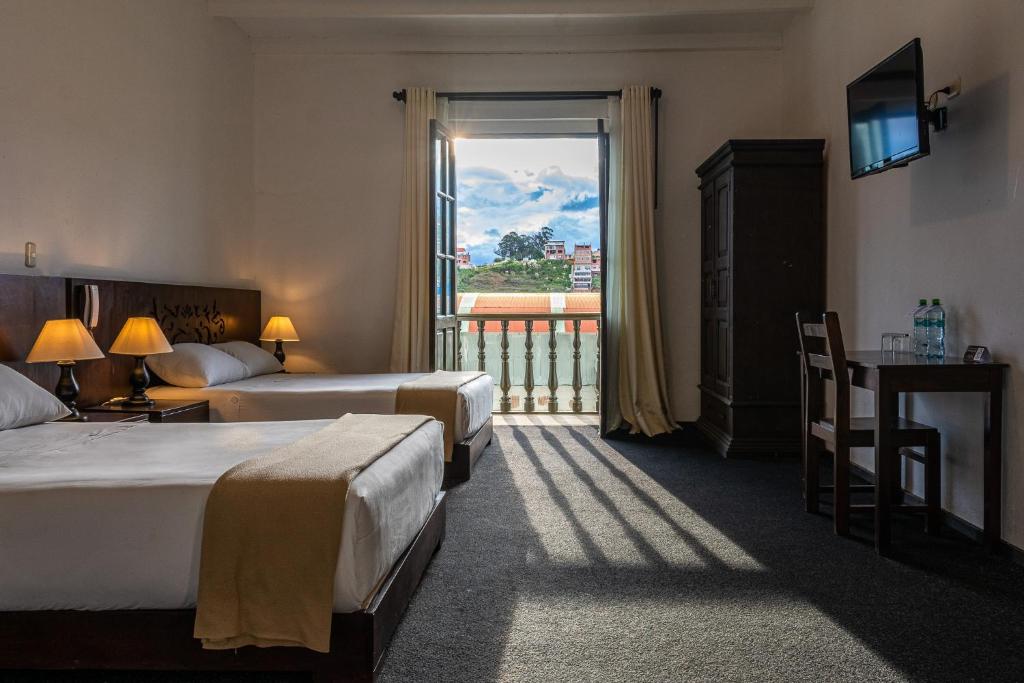 a hotel room with two beds and a large window at La Xalca Hotel - Asociado Casa Andina in Chachapoyas