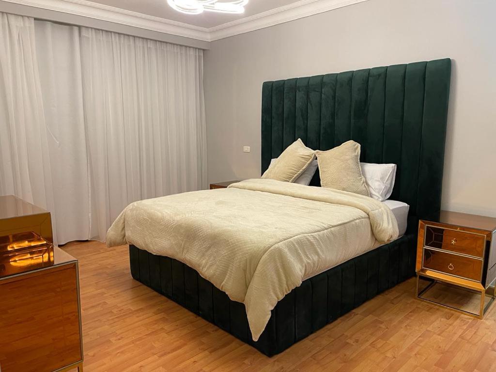 a bedroom with a large bed with a green headboard at Duplex in westown beverly hills in Sheikh Zayed