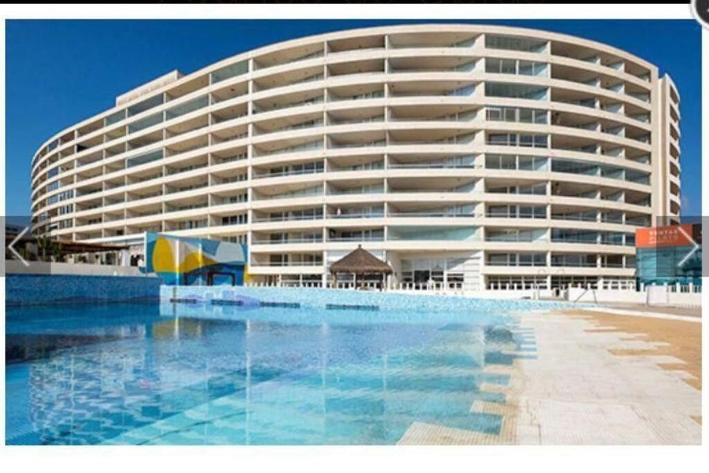 a large building with a swimming pool in front of it at Departamento frente al mar YMAS in La Serena