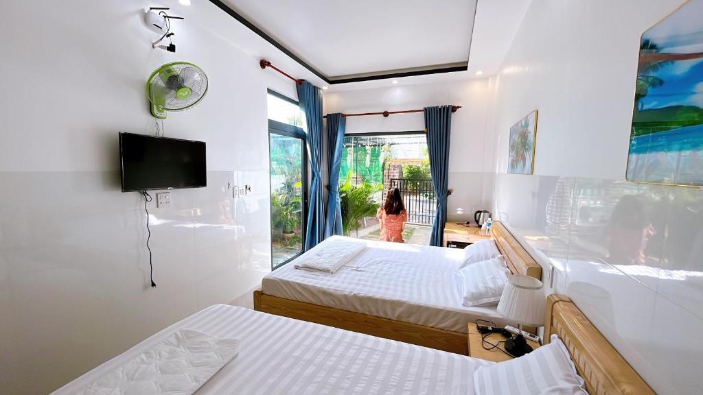 una habitación con 2 camas y una mujer mirando por la ventana en Bảo Phúc Bungalow- Đảo Phú Quý, en Cu Lao Thu