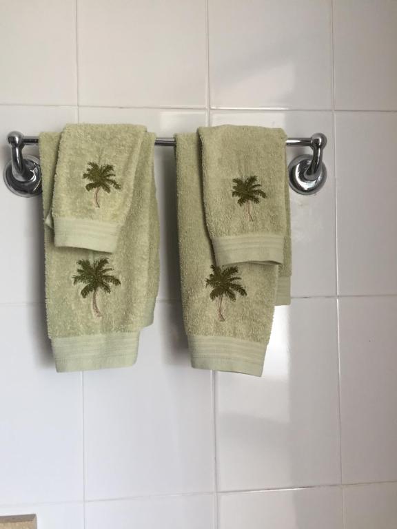 3 toallas con palmeras colgando en un estante del baño en areia beach paradaise, en Santa Marta