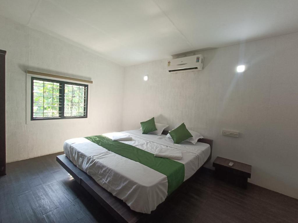 a bedroom with a large bed with green pillows at Misty Ghats Resort in Wayanad