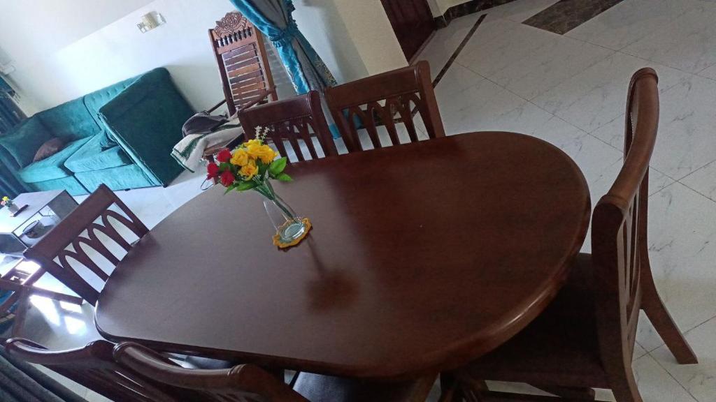 een houten tafel met een vaas met bloemen erop bij Charang House in Phnom Penh