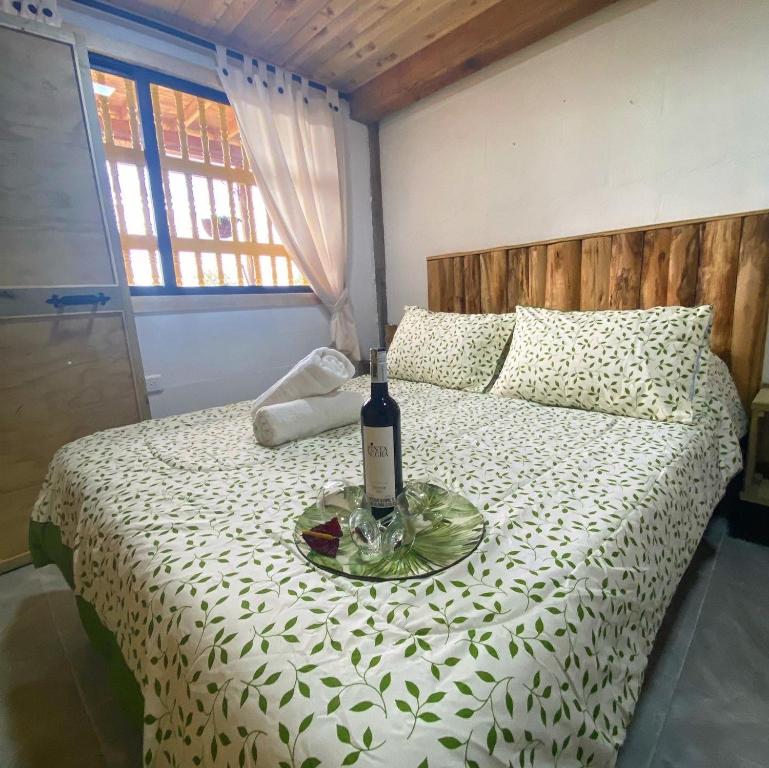 eine Flasche Wein auf einem Teller auf dem Bett in der Unterkunft Bio Cabaña Maria Guadalupe in Rionegro