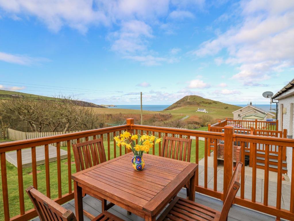 a wooden table with a vase of flowers on a deck at Llaethdy in Cardigan