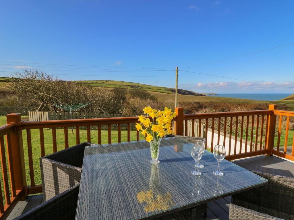 einen Tisch mit zwei Weingläsern und Blumen auf dem Deck in der Unterkunft Beudy in Cardigan