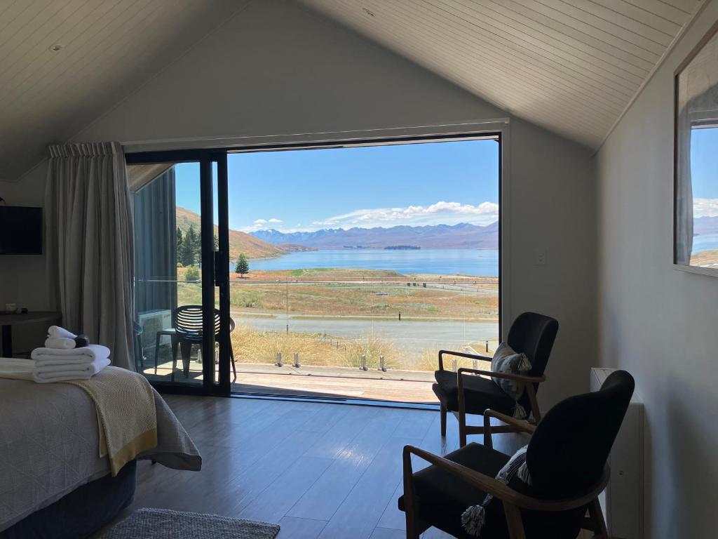 a bedroom with a large window with a view of the water at The Quarters Unit 1 - Lake Tekapo in Lake Tekapo