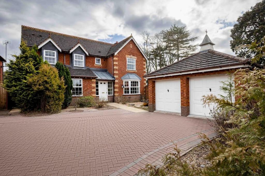 a brick house with two white garage doors at Spacious 5 bedroom house in quiet cul-de-sac in Shrewsbury