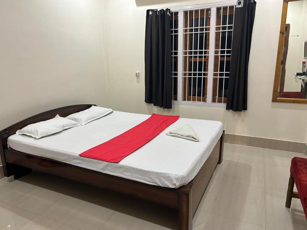 Un dormitorio con una cama con una raya roja. en Flagship Jbs Eco Stay, en Kāziranga