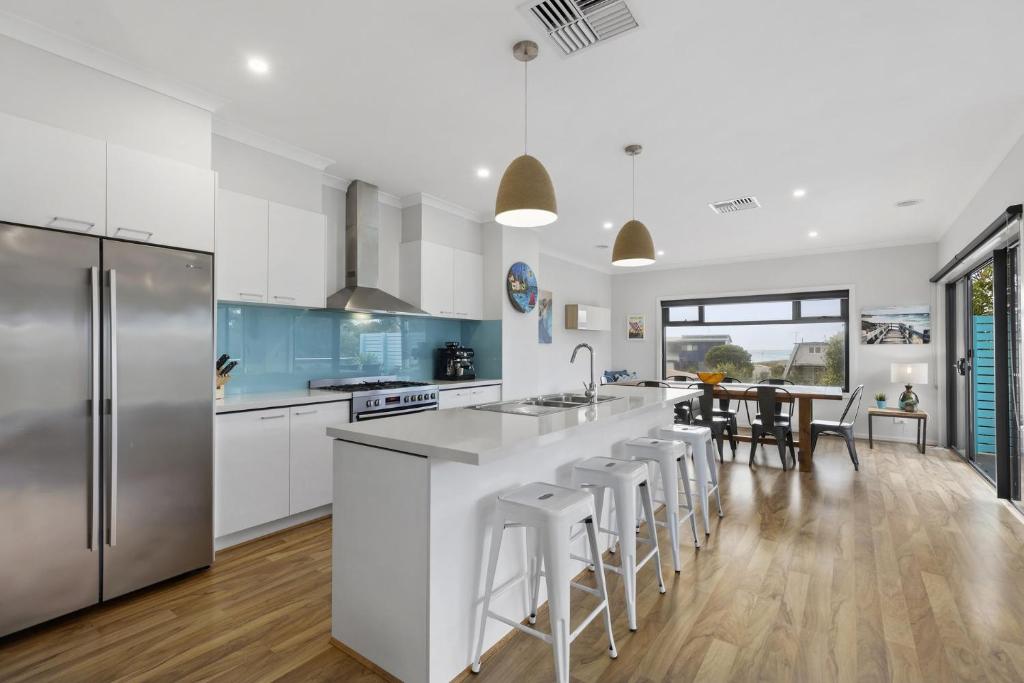 a kitchen with white cabinets and stainless steel appliances at Beach Gum in Apollo Bay