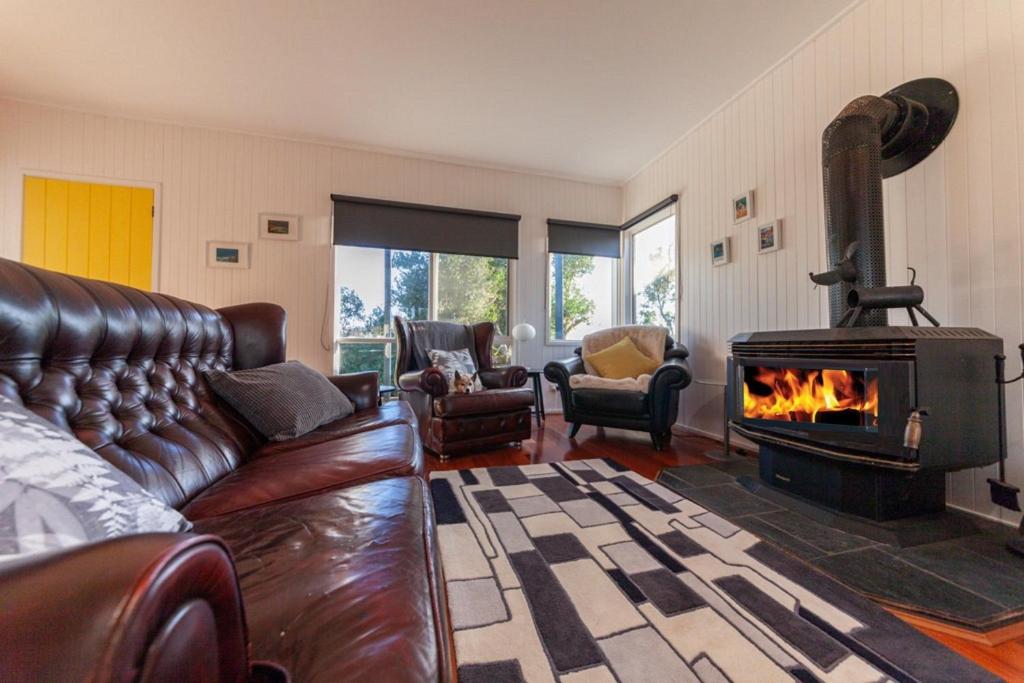 sala de estar con sofá de cuero y chimenea en The Albatross, en Port Campbell