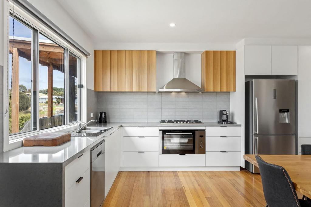 uma cozinha com armários brancos e um forno com placa de fogão em Aurora em Apollo Bay