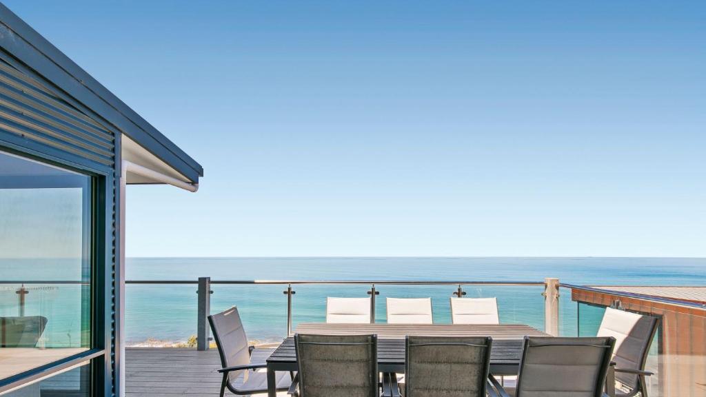 a dining table and chairs on a balcony with the ocean at The Blue House in Wye River