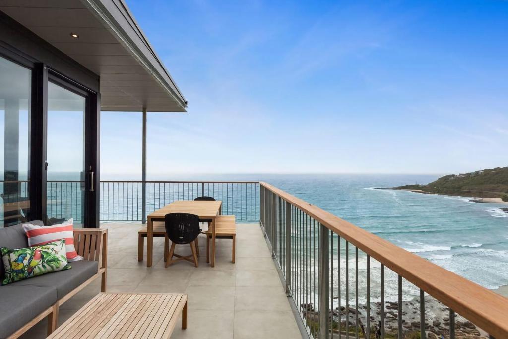 a balcony with a table and chairs and the ocean at At Wye Eyrie II in Wye River