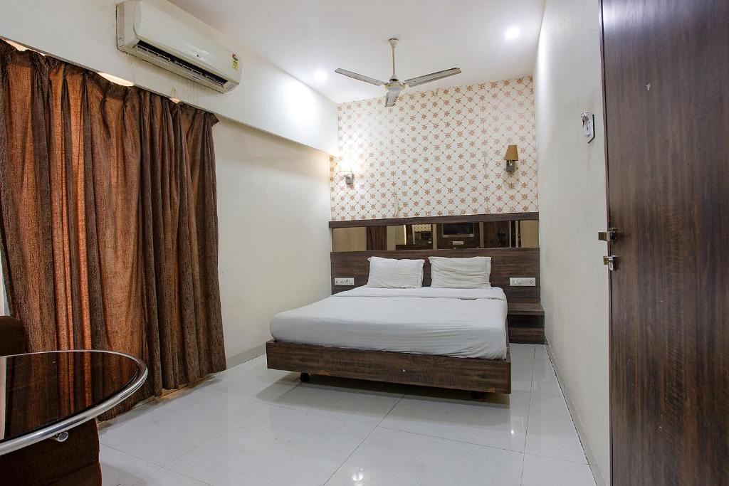 a small bedroom with a bed and a window at Via Shivani Residency in Mumbai