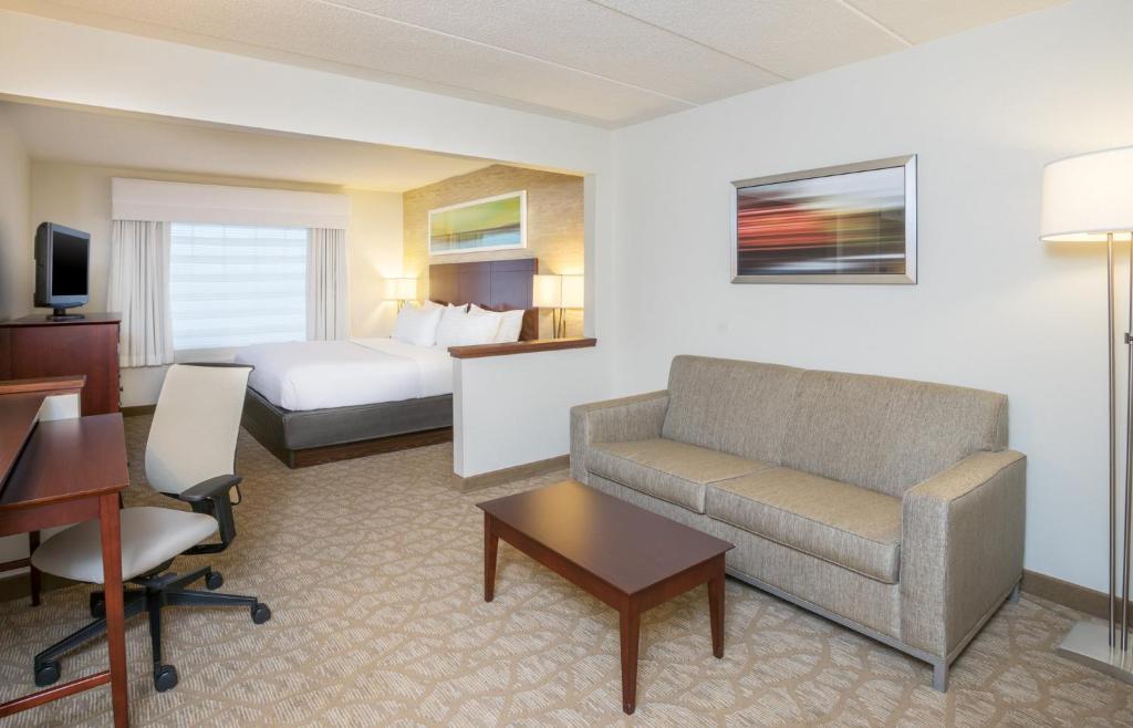 a hotel room with a bed and a couch and a desk at Holiday Inn Baltimore BWI Airport by IHG in Linthicum Heights