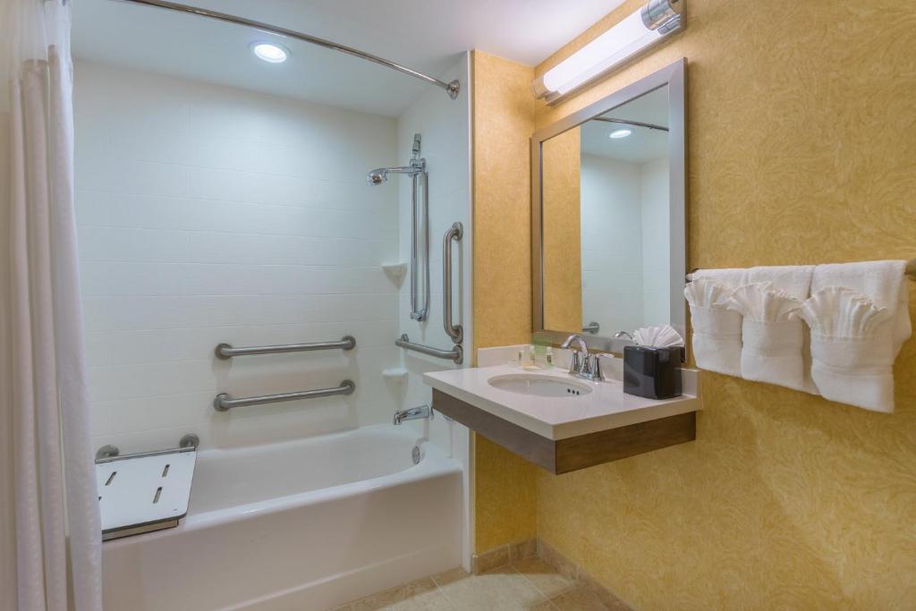 a bathroom with a sink and a tub and a shower at Holiday Inn Baltimore BWI Airport by IHG in Linthicum Heights