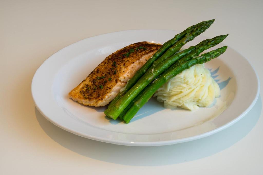 a plate of food with a piece of fish and asparagus at Holiday Inn Baltimore BWI Airport by IHG in Linthicum Heights