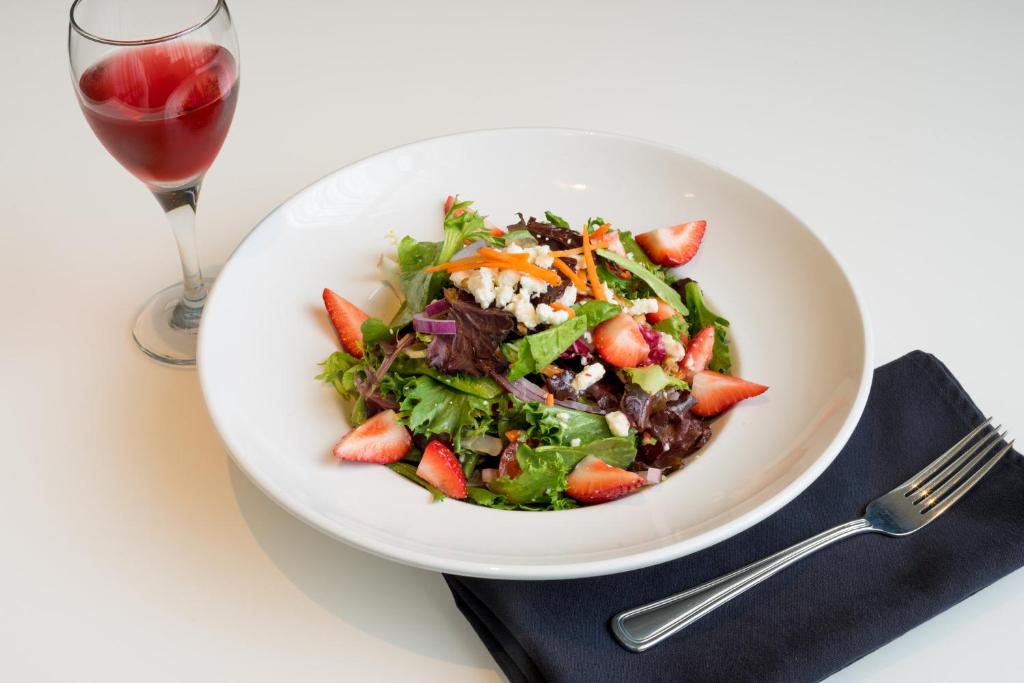 a salad in a white bowl next to a glass of wine at Holiday Inn Baltimore BWI Airport by IHG in Linthicum Heights