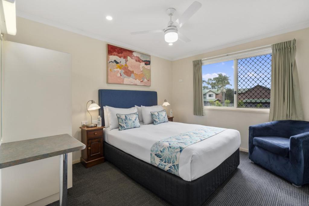 a bedroom with a bed and a blue chair at Caboolture Central Motor Inn, Sure Stay Collection by BW in Caboolture