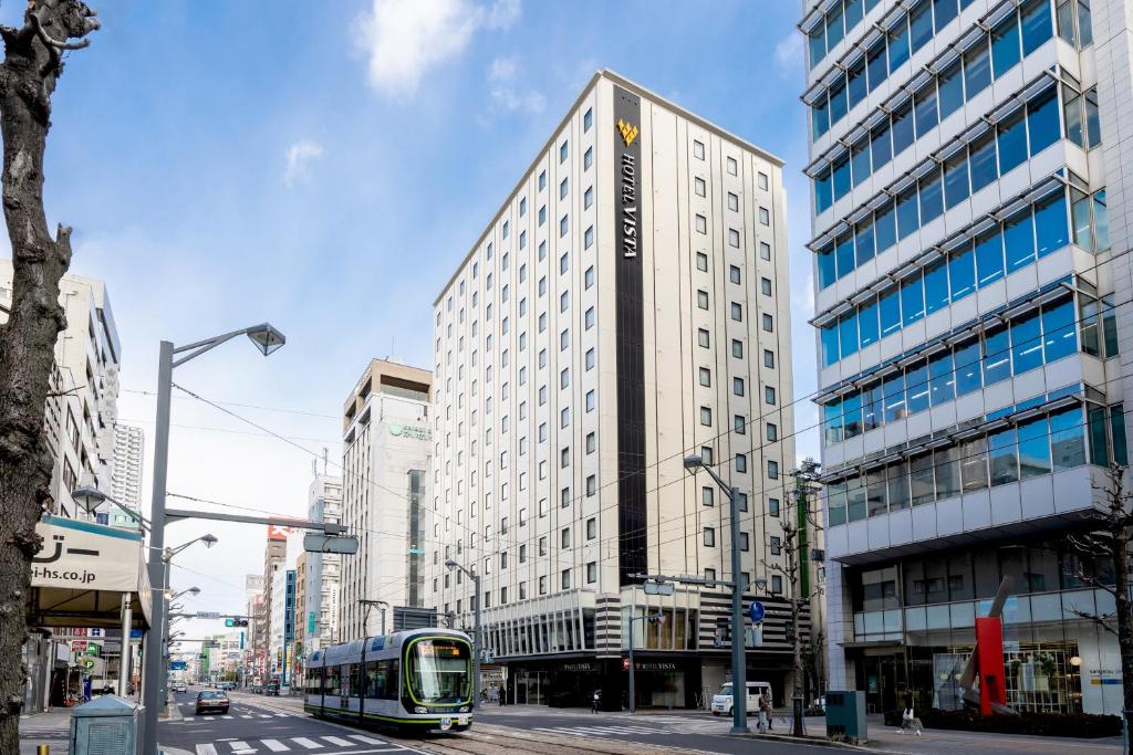 a bus on a city street with a tall building at Hotel Vista Hiroshima in Hiroshima