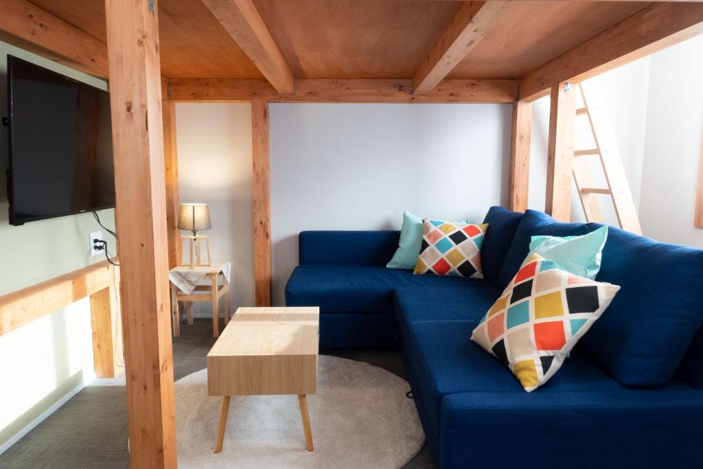 uma sala de estar com um sofá azul e uma televisão em 池袋Apila em Tóquio