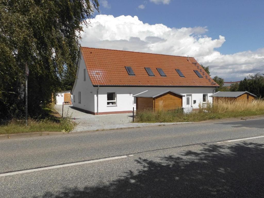 a white house with an orange roof on the side of a road at Haus Horst - Schwerin-Görries in Klein Rogahn