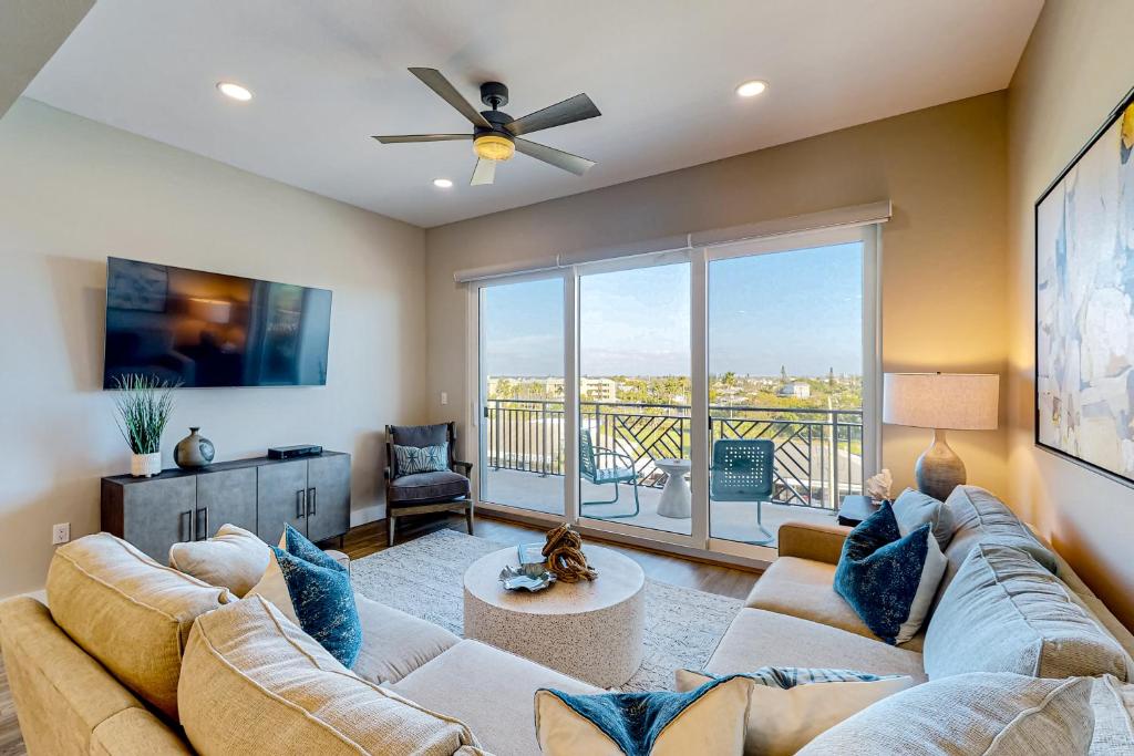 a living room with a couch and a ceiling fan at Penthouse Sweet in St. Pete Beach