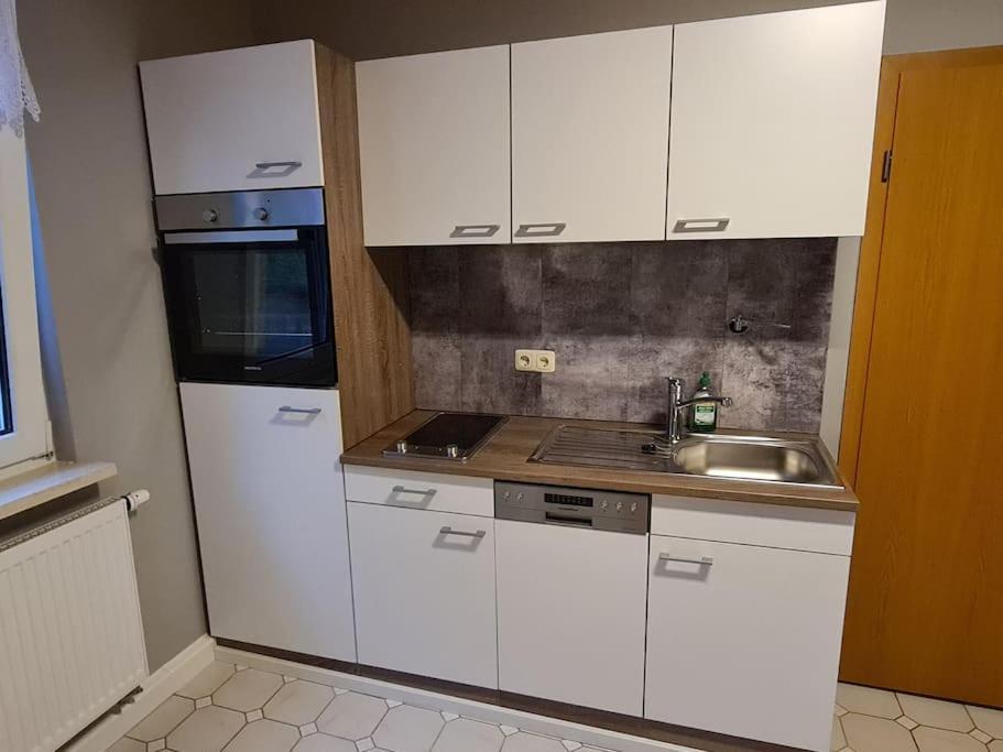 a kitchen with white cabinets and a sink at Schönes Doppelzimmer mit Küche und Badezimmer in Elgersburg