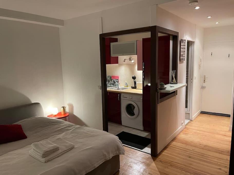 a room with a bed and a kitchen with a washing machine at Studio quartier historique in Rouen