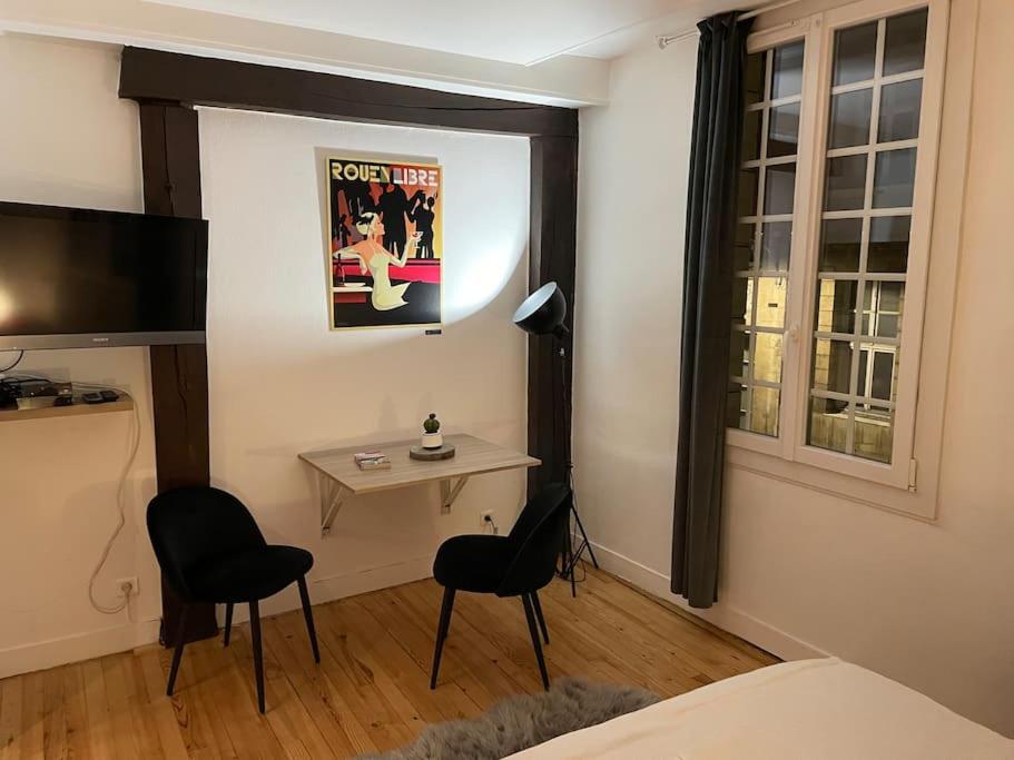a bedroom with a desk and two chairs and a television at Studio quartier historique in Rouen