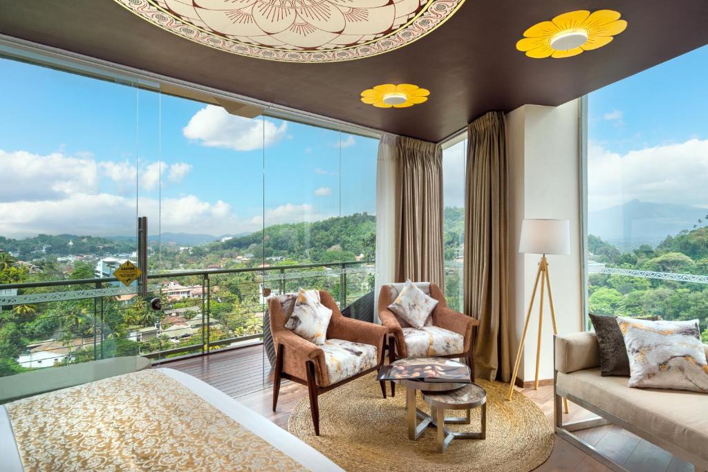a bedroom with a bed and chairs and a large window at Grand Serendib Hotel in Kandy