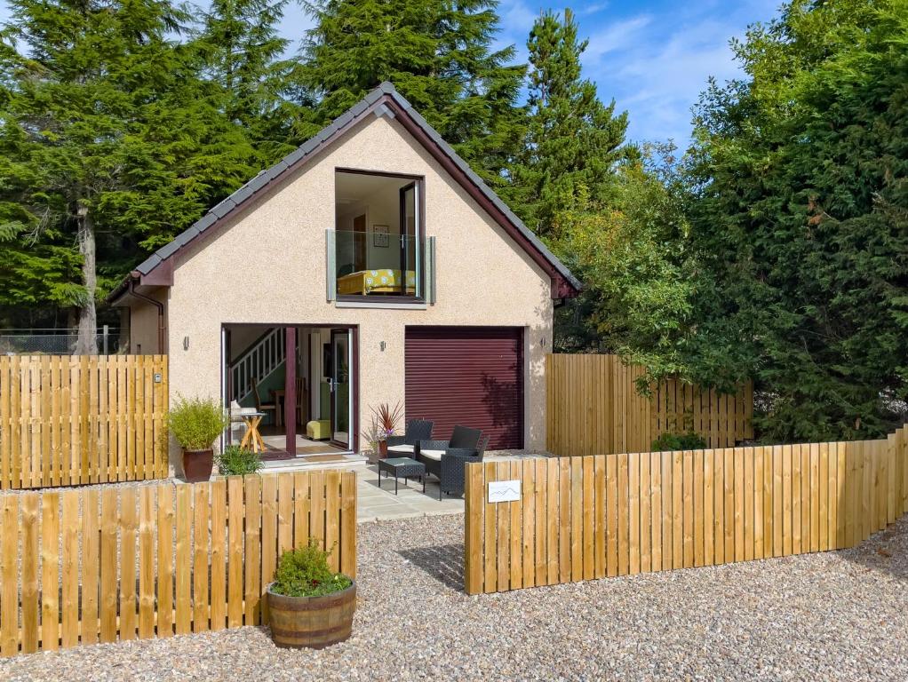 ein Haus mit einem Holzzaun davor in der Unterkunft Taighsona Bothy, Speyside - amazing views! in Archiestown