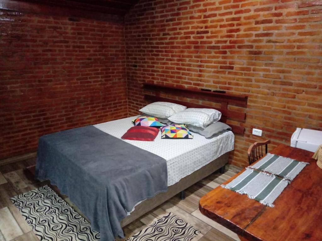 a bedroom with a bed in a brick wall at Chalés Pedacim du Céu in Bueno Brandão