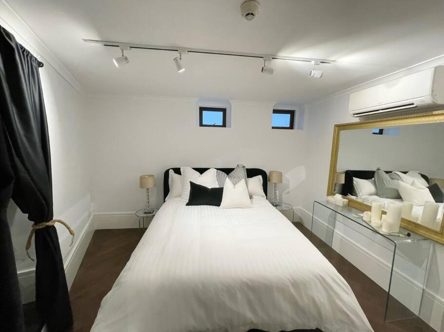 a bedroom with a white bed with a large mirror at The mini New-Yorker in Sydney