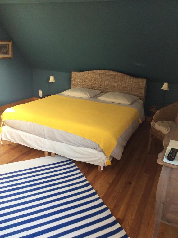 um quarto com uma cama grande e um cobertor amarelo em La VILLA en BAIE em Le Crotoy