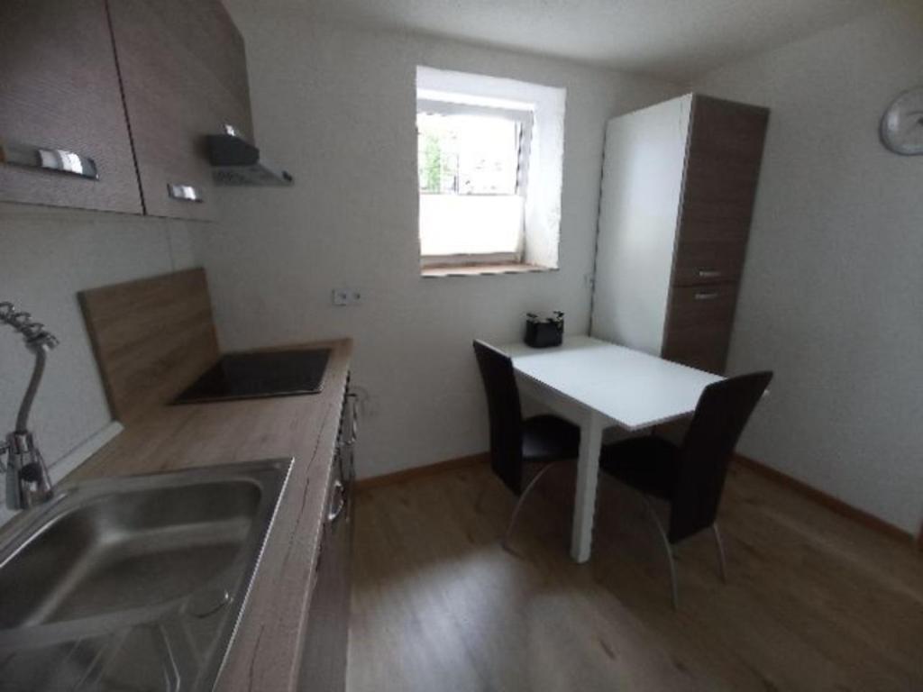 a small kitchen with a table and a refrigerator at NEU FeWo Oels Großalmerode in Großalmerode