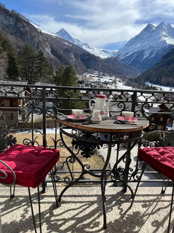 een tafel en stoelen op een balkon met uitzicht op de bergen bij Heida, studio ensoleillé au village avec magnifique vue sur la Dent-Blanche in Evolène