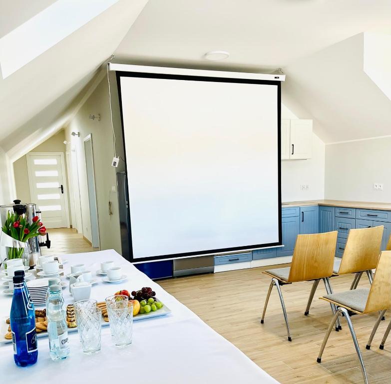 a large screen in a room with a table and chairs at Osada Chmiel in Chmielno