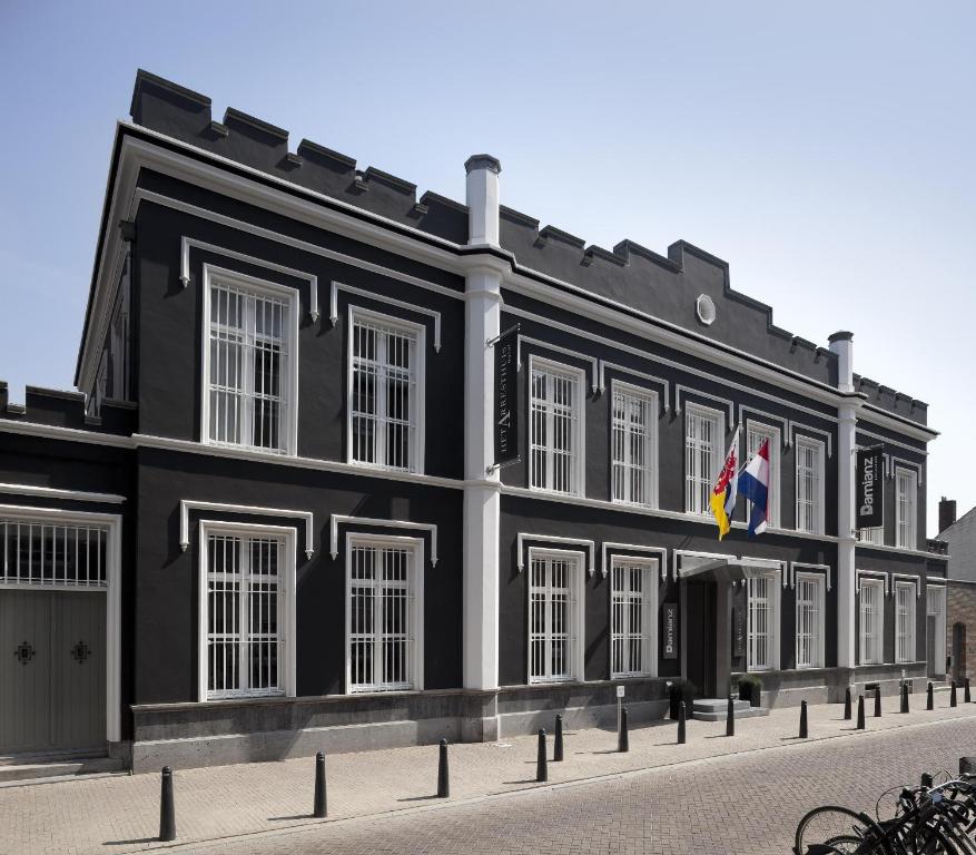 een zwart gebouw met twee vlaggen ervoor bij Het Arresthuis in Roermond