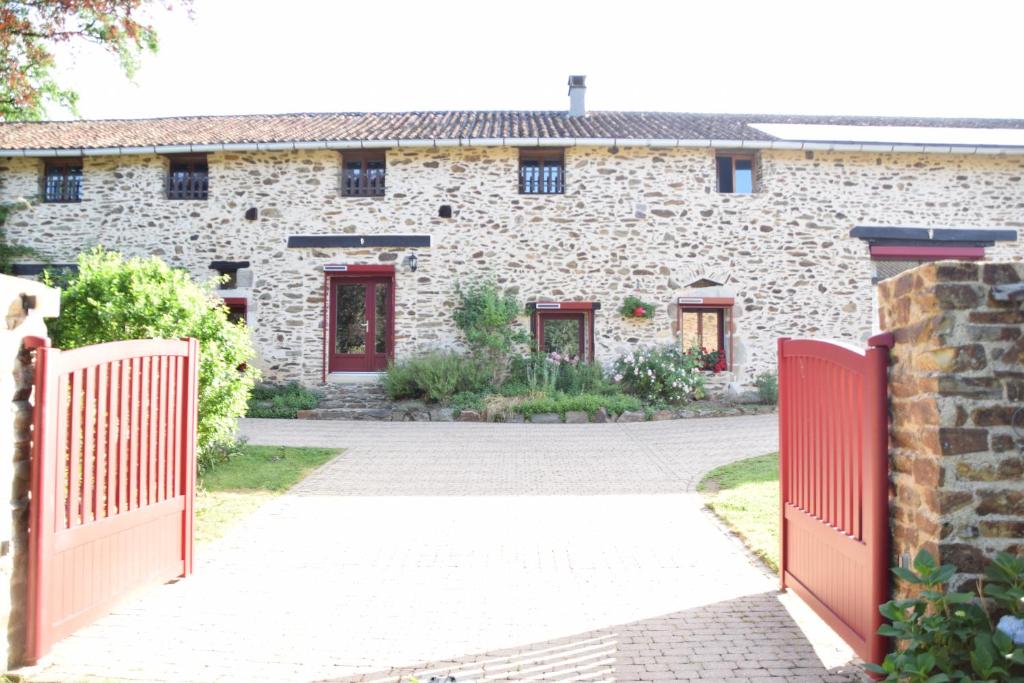 une maison en pierre avec un portail rouge et une allée. dans l'établissement LES 2 CHENES, à Les Riffes