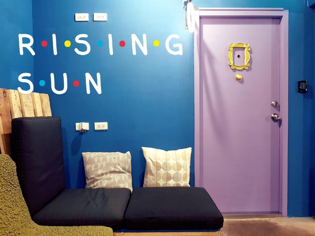 Hostel of Rising Sun 昇行旅 في تايبيه: باب أرجواني مع أريكة أمام الجدار الأزرق