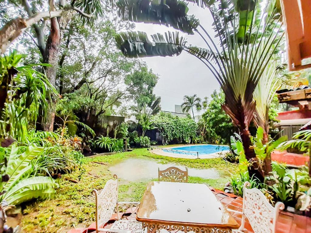 einen Garten mit einem Tisch und Stühlen sowie einem Pool in der Unterkunft Chito's Hotel in Iloilo City