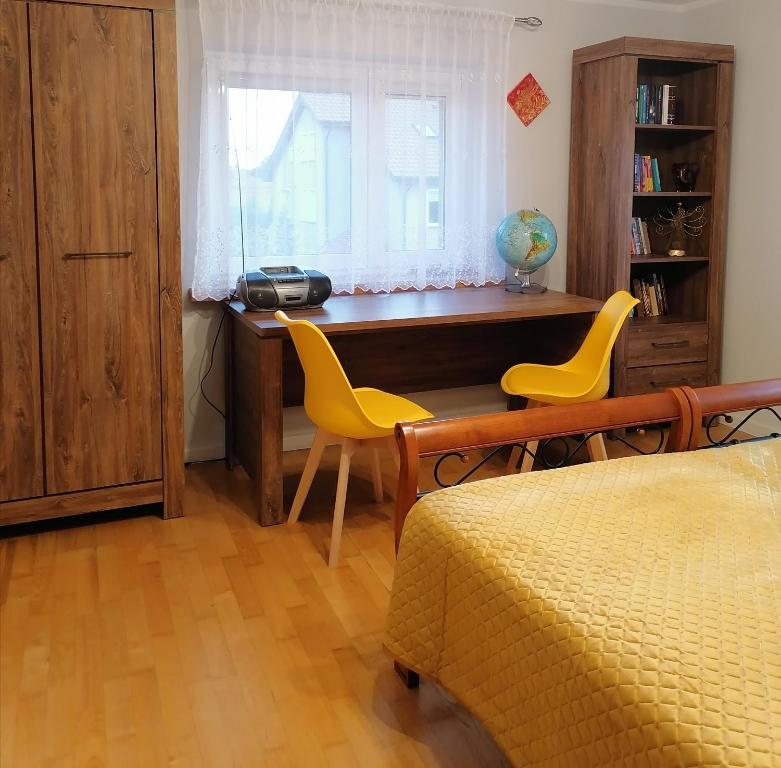 - une chambre avec un bureau et deux chaises jaunes dans l'établissement Apartament Wschód Słońca Olecko, à Olecko
