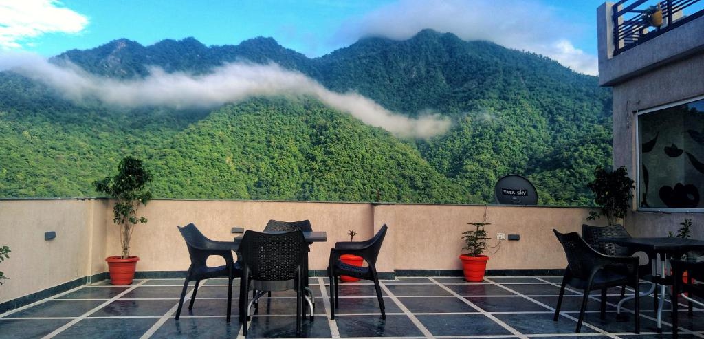 a table and chairs on a balcony with a mountain view at Back Stayz Hostel in Rishīkesh