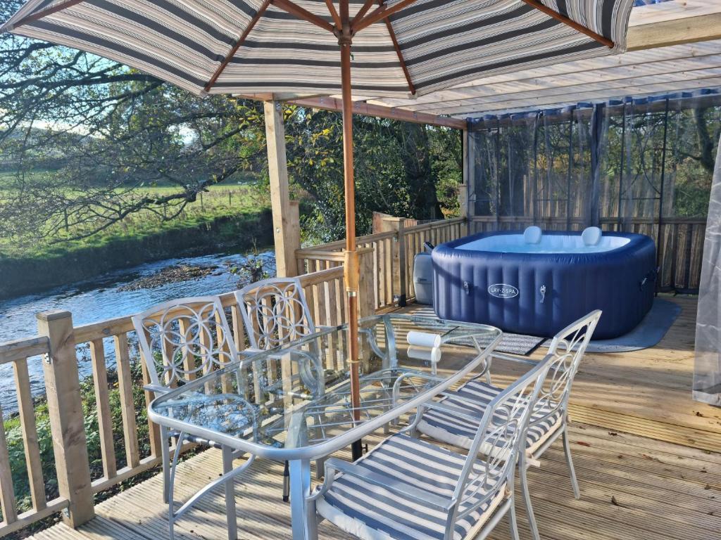 a table and chairs under an umbrella on a deck at Riverside Cabin at Pen-Y-Bont Mill in Oswestry
